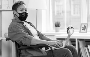 Photo of a woman with a disability in a wheelchair wearing a medical mask to prevent Covide-19