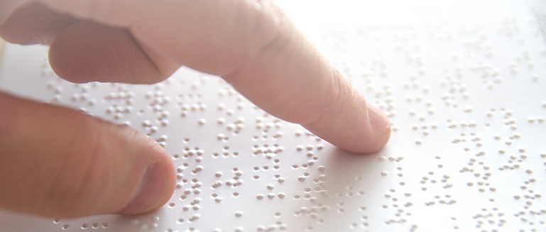 Close-up of a persons hand reading a braille document
