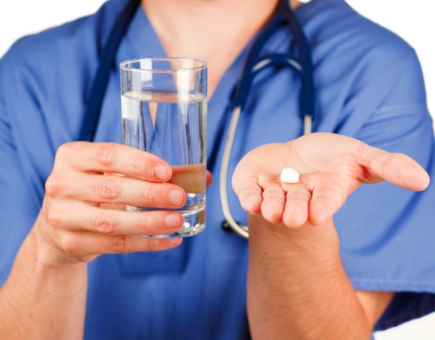 Stock photo of a nurse handing you a glass of water and meds.