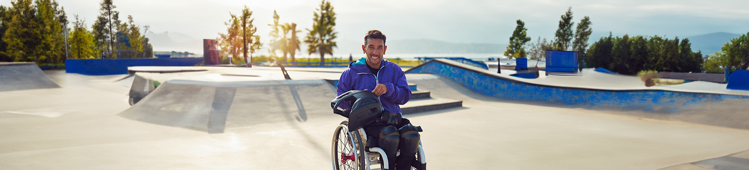 A portrait of a smiling athlete man with disability in wheelchair at skatepark.