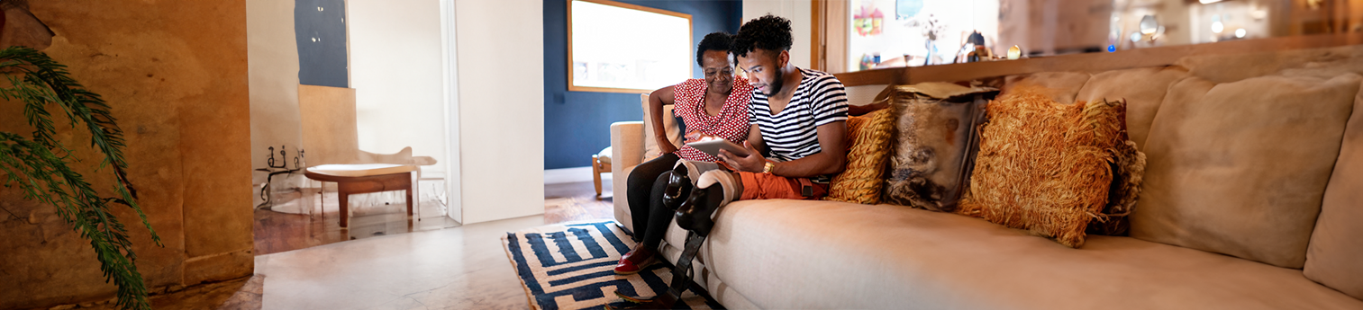 A black mother and son with a prosthetic leg looking at a tablet for information.