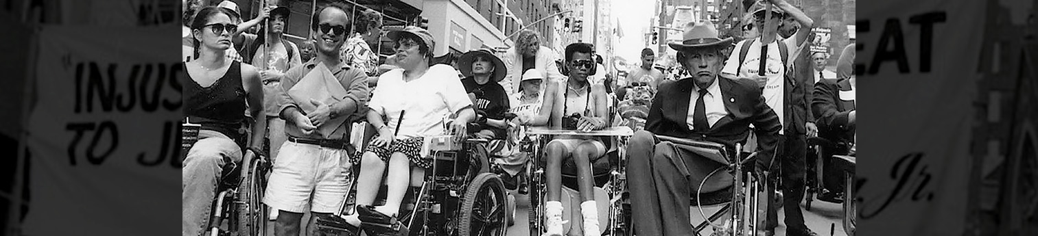 Participants in one of the first Disability Independence Day marches in New York City gathered under a banner that reads “‘Injustice Anywhere is a Threat to Justice Everywhere,’—Martin Luther King, Jr.”