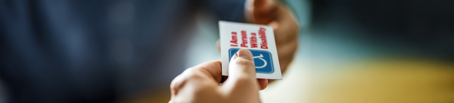 A person with a disability handing another person their disability accommodations card