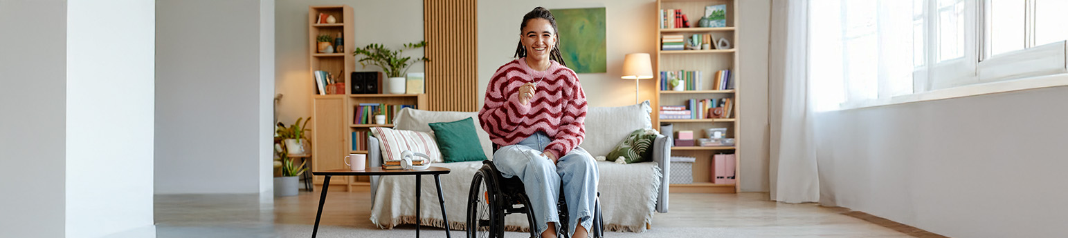 A latina woman with braids in a wheelchair in her living room.