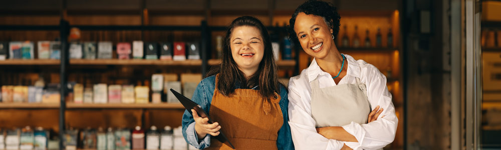 A young woman with a mental disability next to her female co-worker at a coffee shop