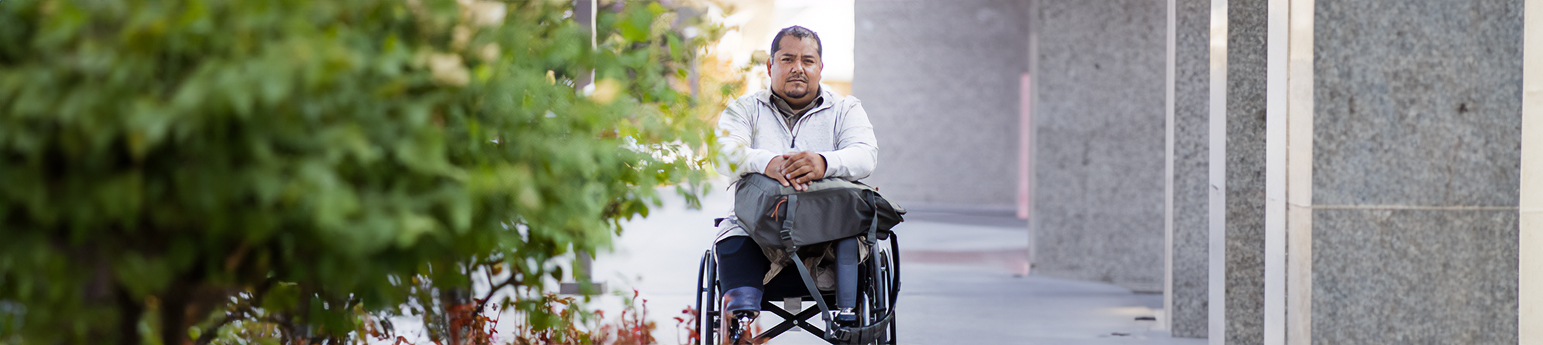 A Latino American in a wheelchair, both of his legs have been amputated and and he has two bionic legs.