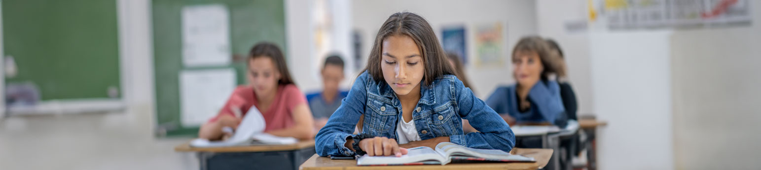 A young girl sitting at her desk in a classroom.