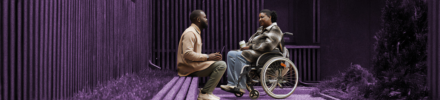 Side view shot of a Black woman in a wheelchair talking to a Black male colleague outdoors in city park.