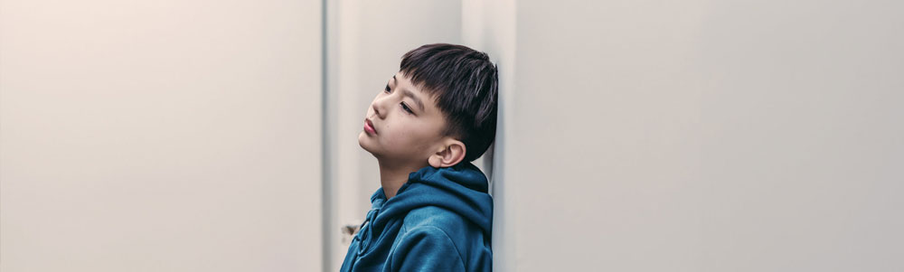 A young boy sitting alone in a room.