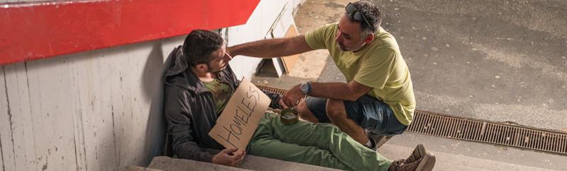 A Polite Man who is Approaching a Unhoused Man who is Sitting on Steps. Kind Man is Helping him by Giving him Support.