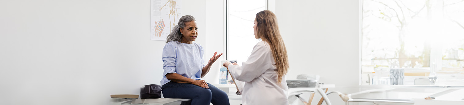 A Black woman with expressing her concerns to a female Latino doctor.