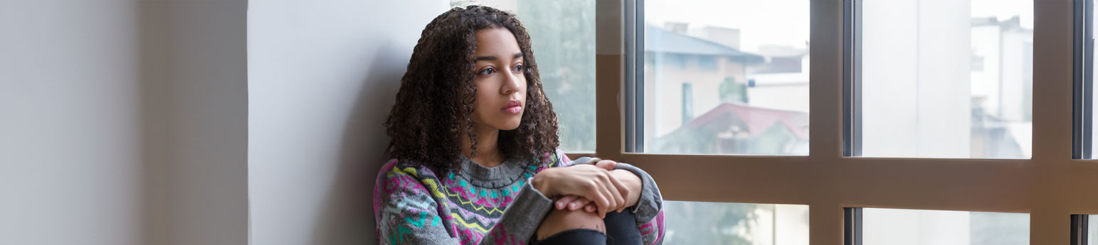 A young girl looking out of a window in a facility.