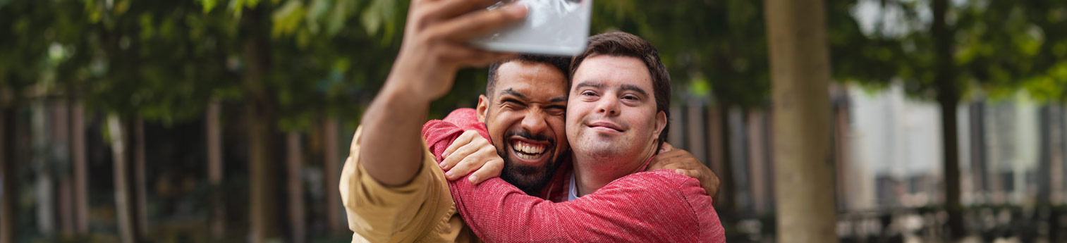 A young man taking a selfie with another young man who has a Down's Syndrome