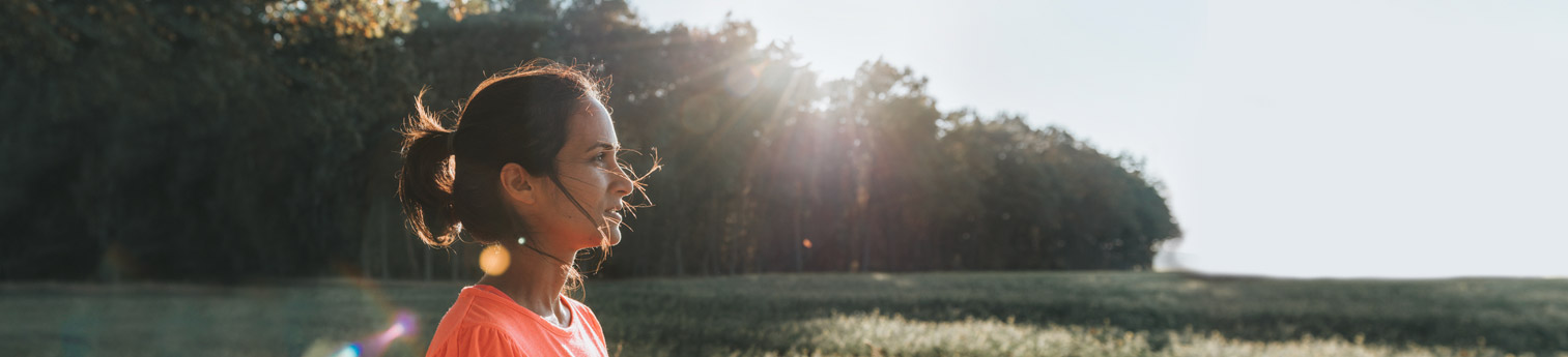 A woman smiling staring off into the sunset on a beautiful day.