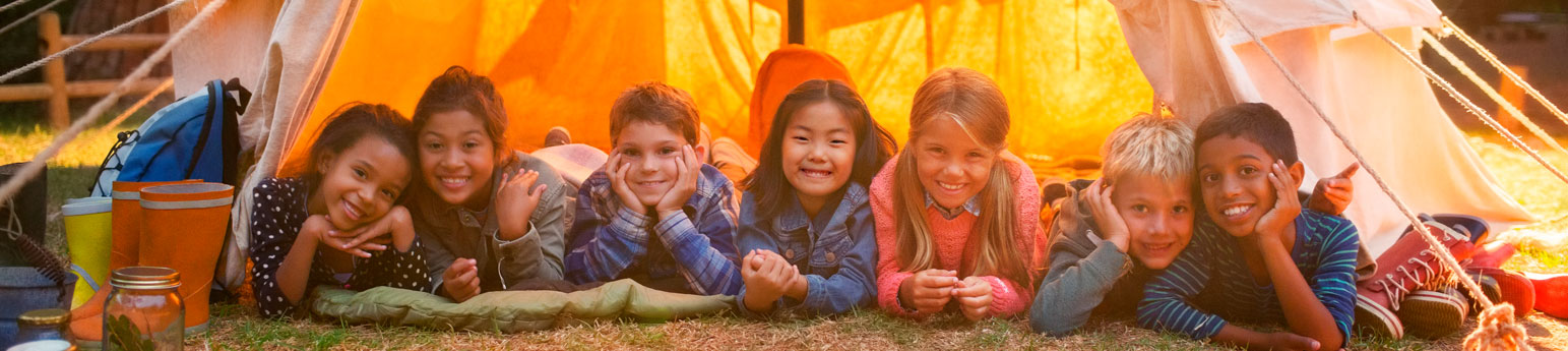 Several children all at the entrance of their tent while they are a camping trip.