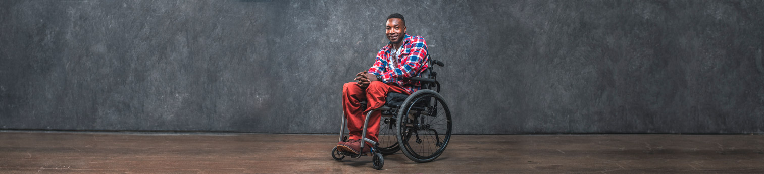 A photo of a black man in a wheel chair in an empty room.