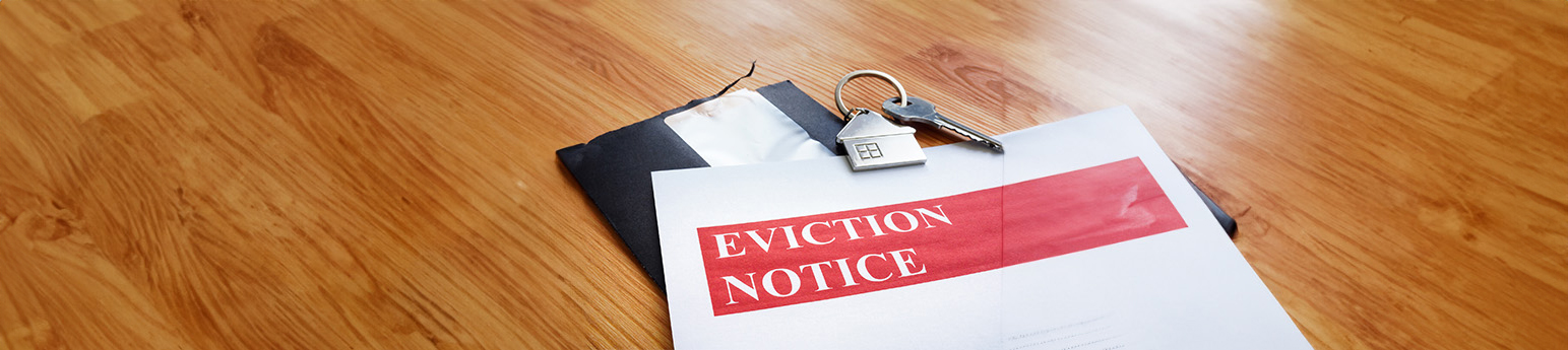 An eviction notice on top of a folder, with a wooden floor background.