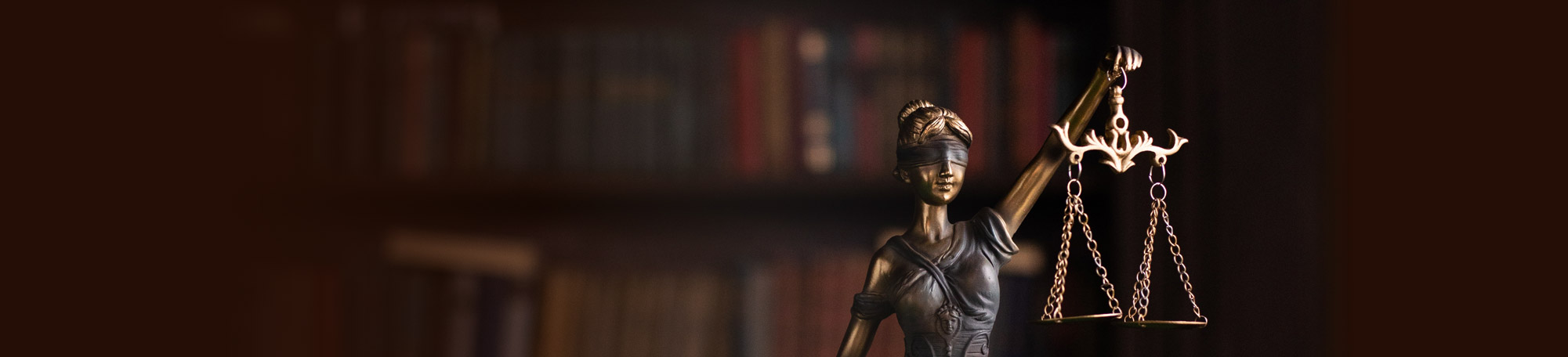 Lady Justice statue in front of a big book case.