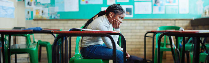 A black female student sitting alone in a classroom