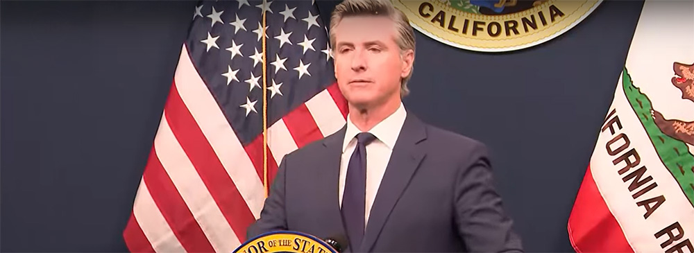 Governor Newsom at a press event behind a podium.