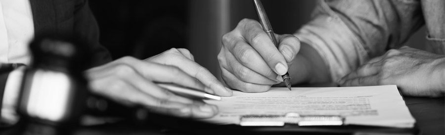 A Black and White closeup photo of a bill being signed.