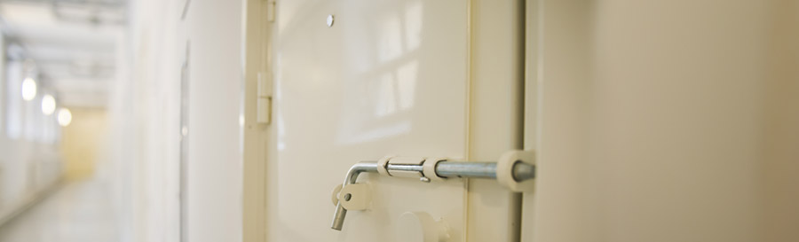 The outside of a solitary confinement cell showing the large latch used to keep it shut.