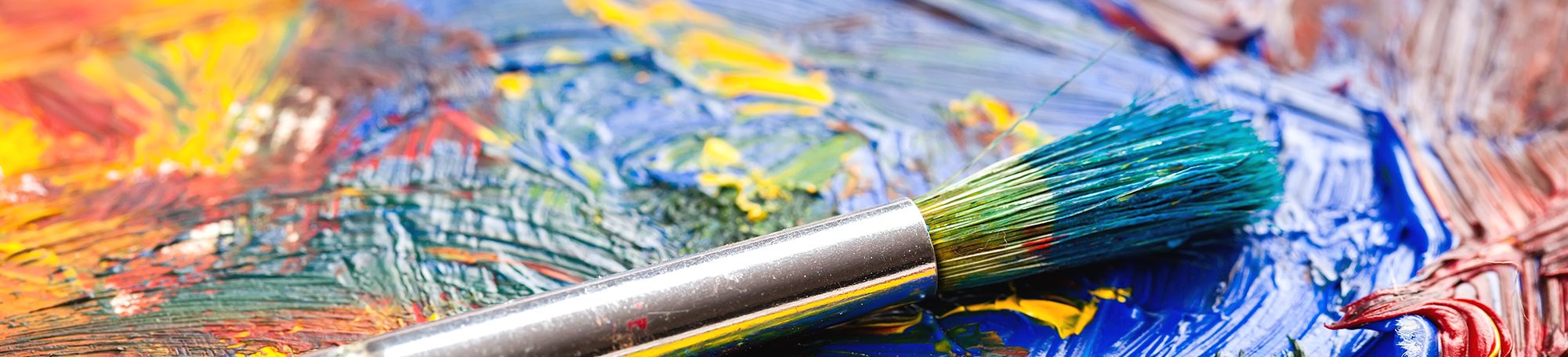 Paint brush covered in paint laying on a paint pallete.