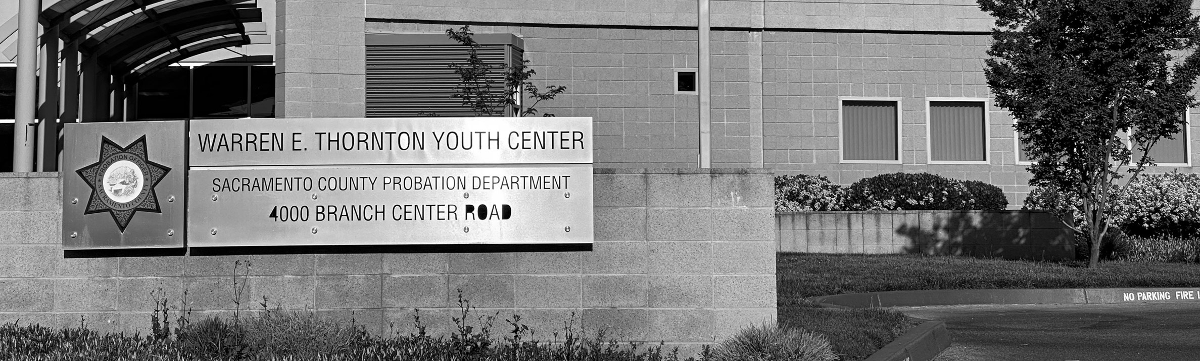 A metal sign in front of the facility that reads - Warren E. Thornton Youth Center, Sacramento County Probation Department, 4000 Branch Center Road.