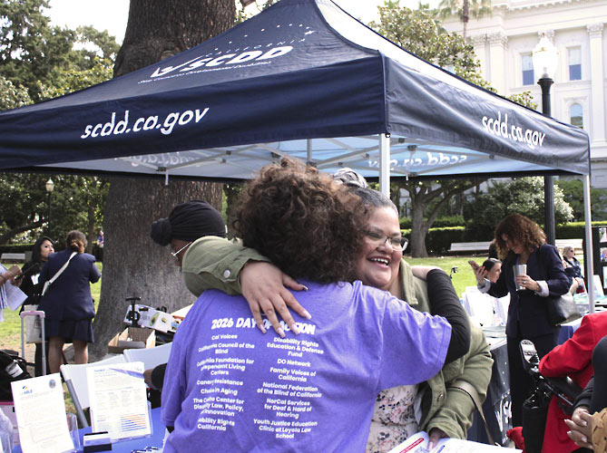 Two women with disabilities hugging each other at the event.