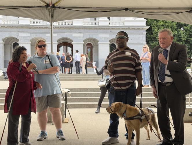 A group af blind adults doing a improv show at the event. There is a seeing eye dog with them.