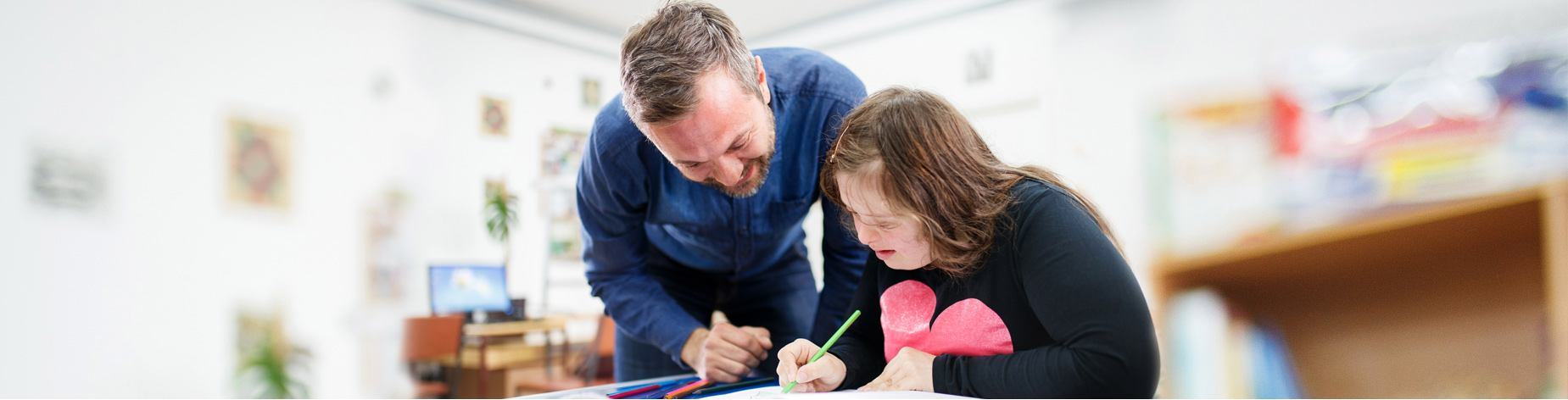 Photo of a teacher helping a female student with a learning disability.