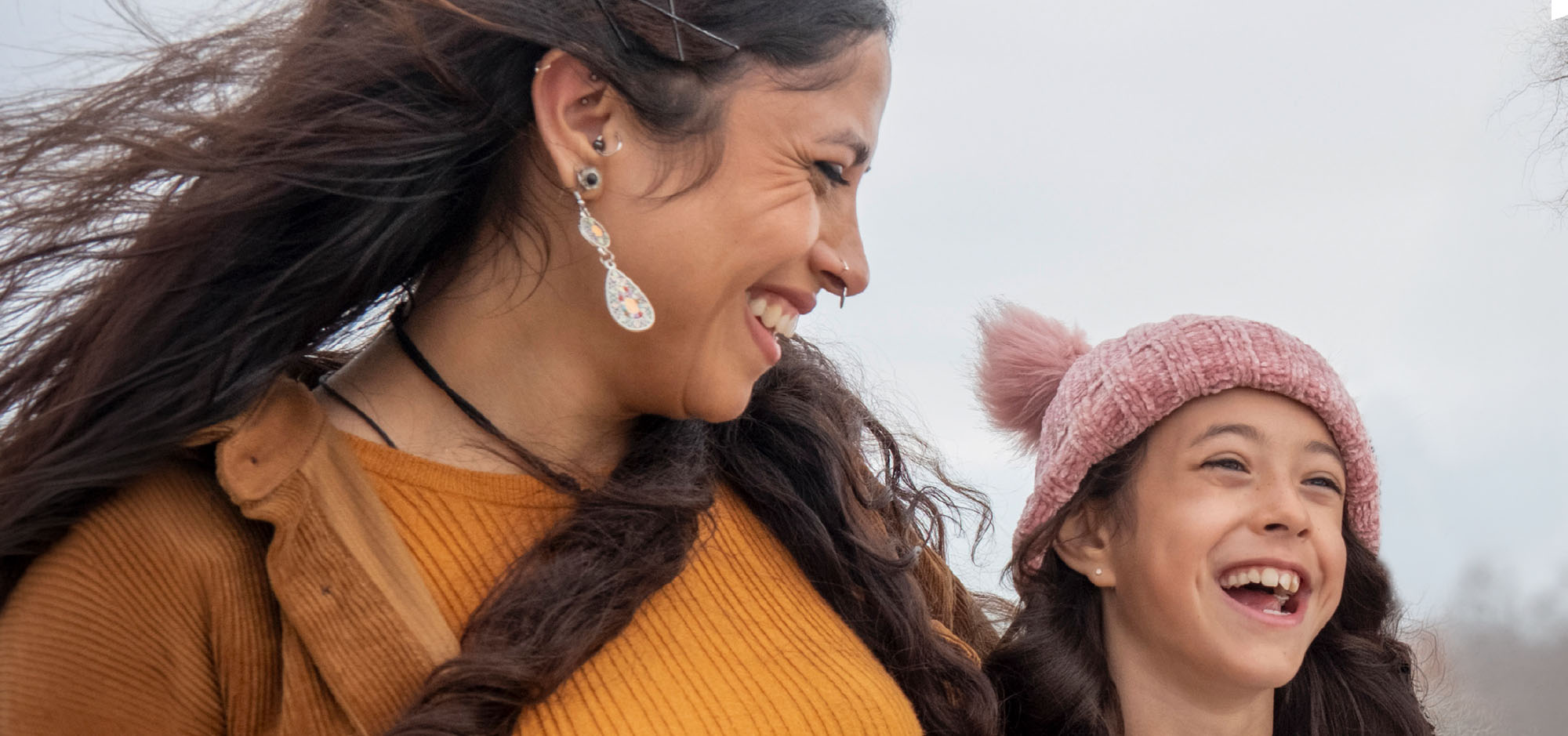 A mother and daughter outside smiling at each other.