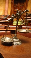 Close up image of justice scales sitting on a table inside a court room.