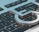 Close up image of a computer keyboard with a metal symbol for disabilities resting on top of it.