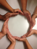 Photo of eight hands forming a circle.