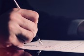 A close up image of a goverment official signing a bill into law.