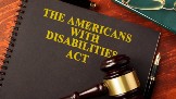 A close up image of a binder with a judges gavel resting on top of it. The cover of the binder says The Americans With Disabilites Act.