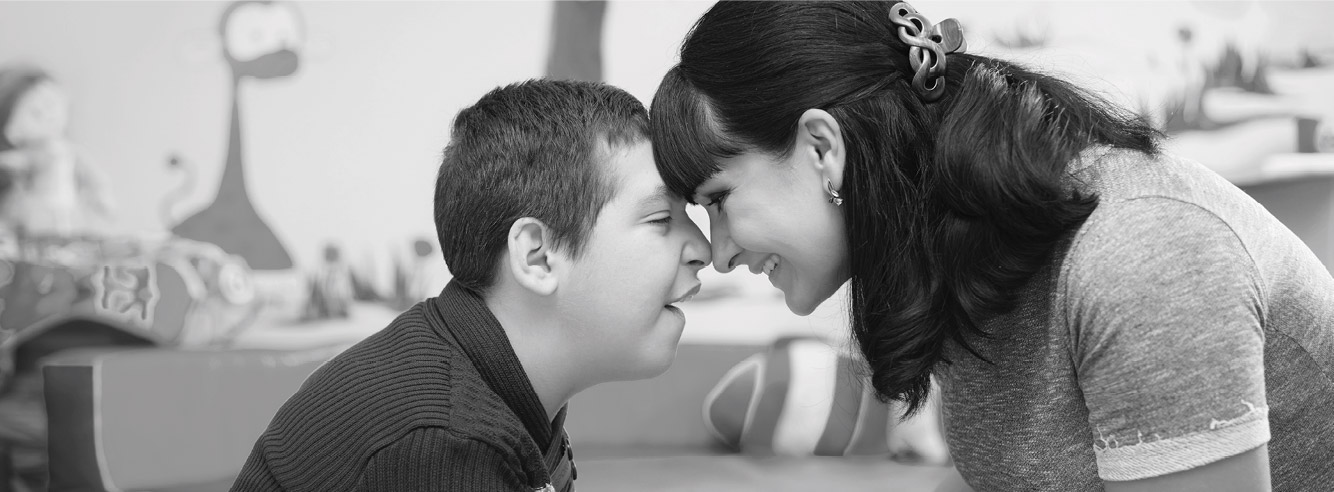 Photo of a woman smiling with a child who has a disability.