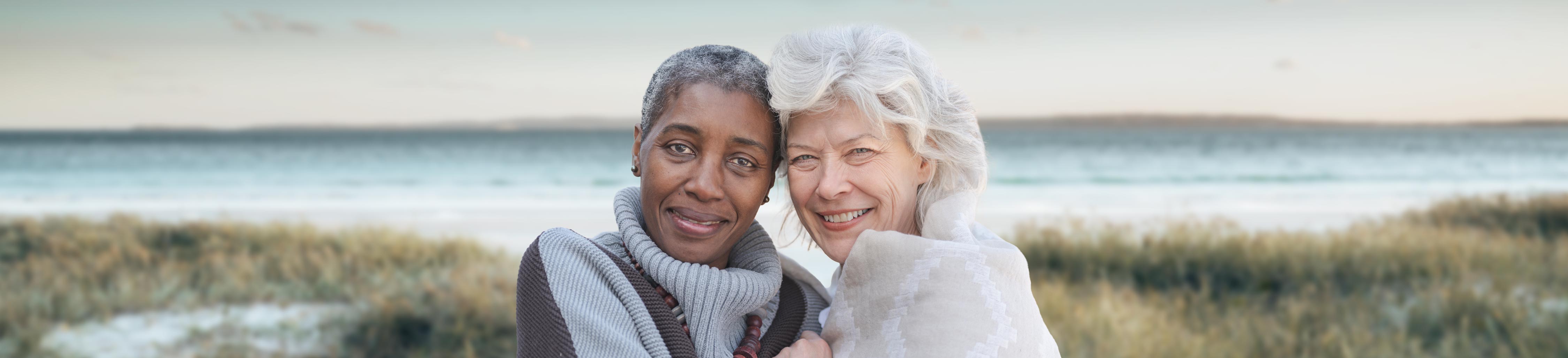 Two women pose for a picture at the beach.