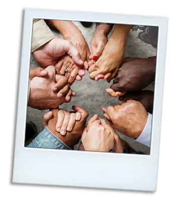 Photo of a group of people of different races with the hands out in a circle.