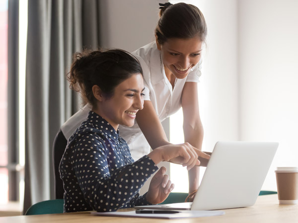 Two woman looking at a laptop reviewing employee benefits.