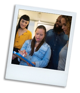 A photo of a young woman with a disability surround by her co-workers at her place of employment.