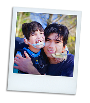 A young boy with a disability hugging his older brother.