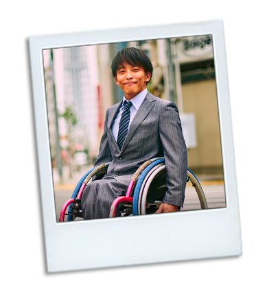 A middle aged man in a wheel chair outside on a sidewalk heading to work.