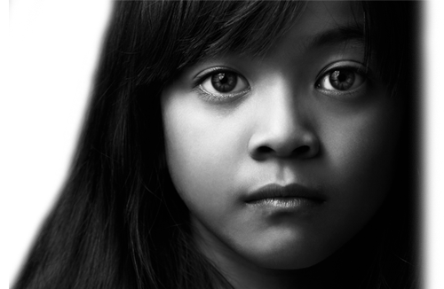 Closeup of the face of a young latino girl. She has a very sad look on her face.