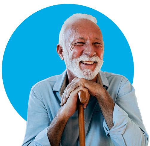 Photo of an elderly man leaning on a cane. He is smiling and happy.