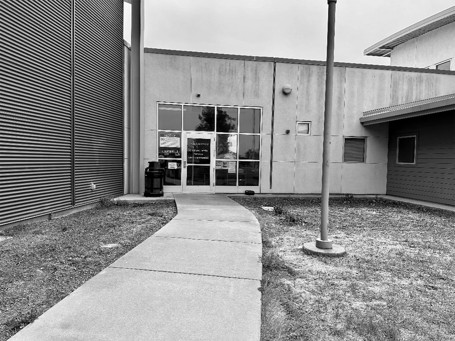 The entrance to the Warren E. Thornton Youth Center. A long concrete walkway leads to a large glass door and glass paneling. The door has a security keycard entry system.