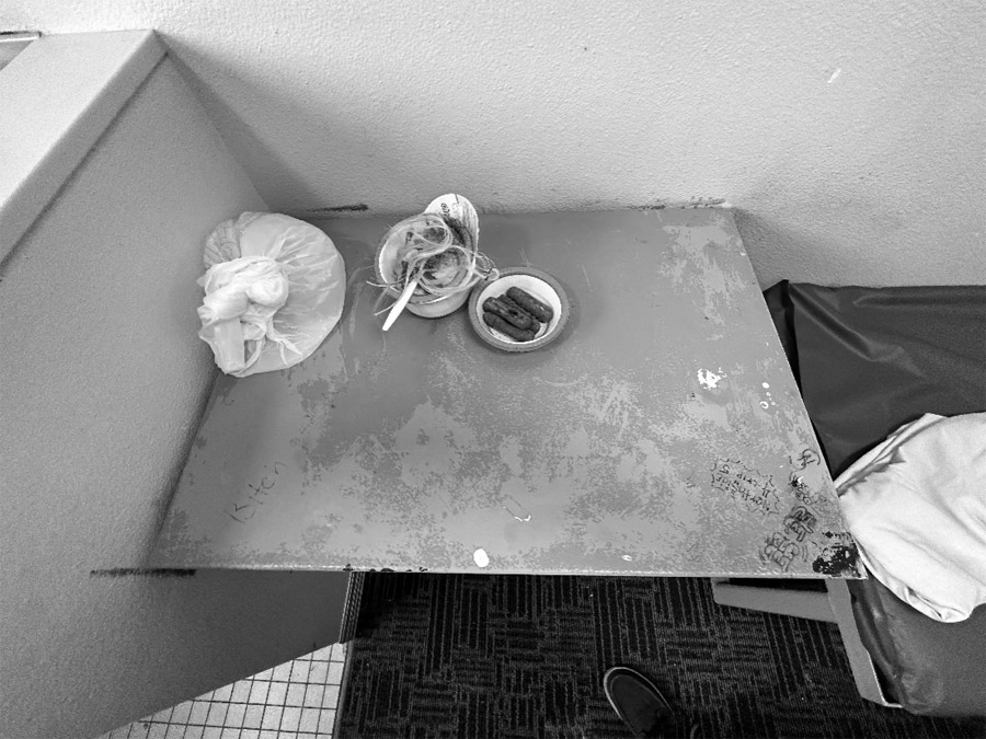 Two bowls of food and a white plastic bag sit on top of a discolored shelf.