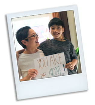 mother and sone holding up a sign that says your are not alone.