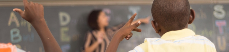 Deaf children face a teacher who is teaching them sign language.
